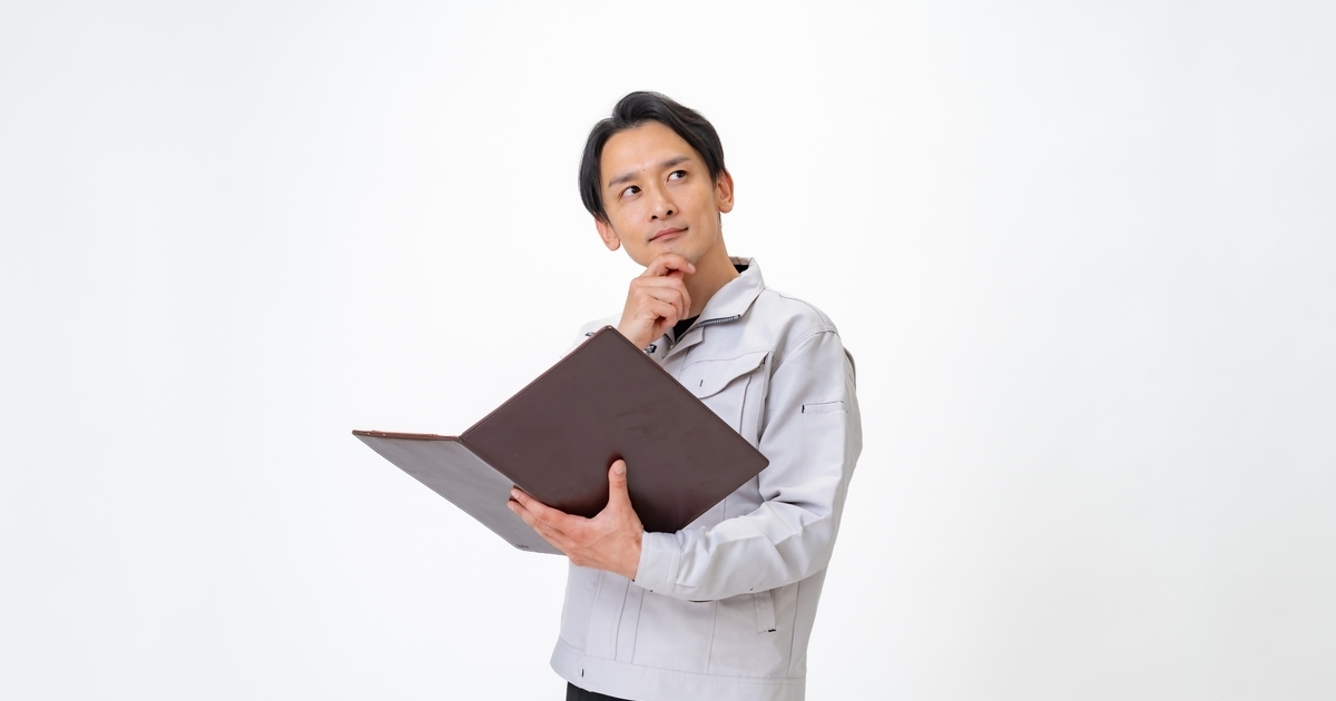 悩んでいる様子の作業着の男性