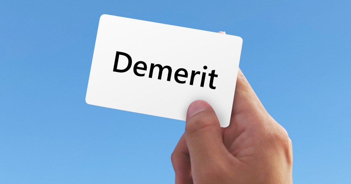 「Demerit」と書かれた紙を持つ手
