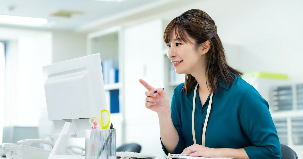 パソコンに向かって指差す女性