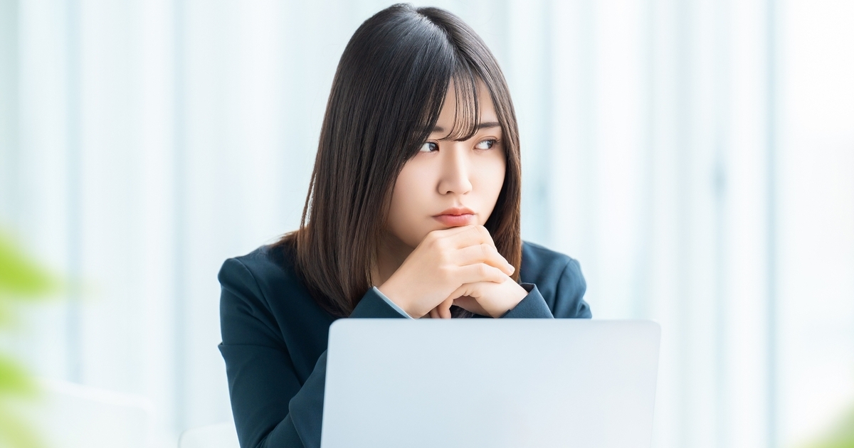 パソコンの前で考え事をする女性